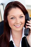 Cheerful businesswoman talking on phone sitting in her office