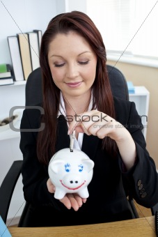 Positive businesswoman putting money into a piggybank 