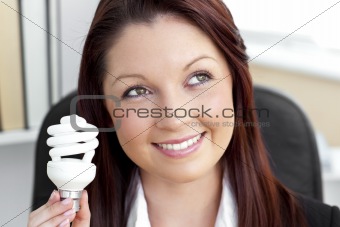 Delighted businesswoman holding a light bulb 