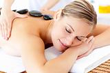 Bright young woman enjoying a back massage with hot stone 
