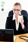 Positive caucasian businesswoman holding a coffee using her lapt