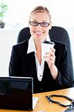 Businesswoman holding coffee working at office with a laptop