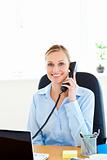 Smiling young businesswoman talking on phone looking at the came
