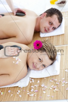 Smiling caucasian couple having a back massage with hot stone 