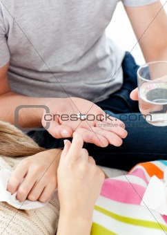 Close-up of young man giving pills to his morbid girlfriend 