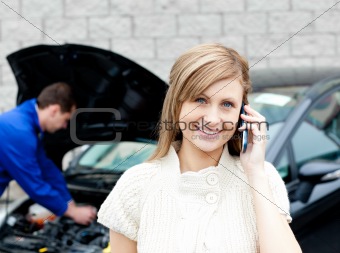 Man repairing car of phoning woman