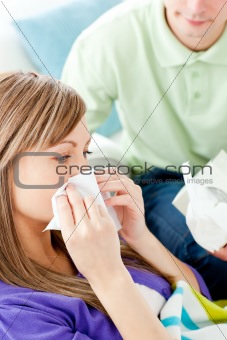 Sick woman with tissue lying on a sofa