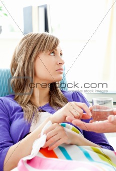 Sick woman with glass of water lying on a sofa
