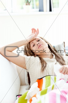 Diseased woman lying on a sofa looking at the camera holding tis