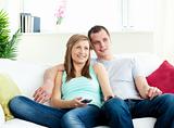 Attentive young couple sitting on the sofa watching tv 