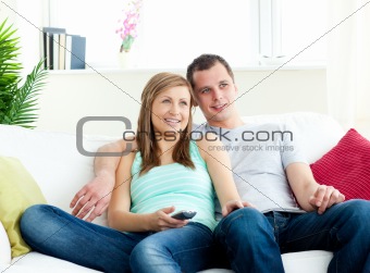 Attentive young couple sitting on the sofa watching tv 