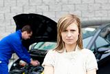 Depressed young woman standing in front of her car 