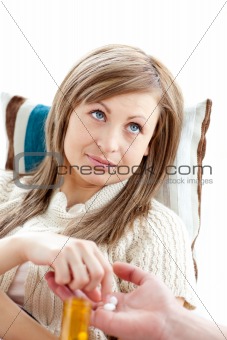 Young sick woman lying on a sofa taking pills from her boyfriend