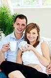 Charming couple holding cups of coffee smiling at the camera 