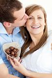 Handsome man kissing his girlfriend holding chocolote 