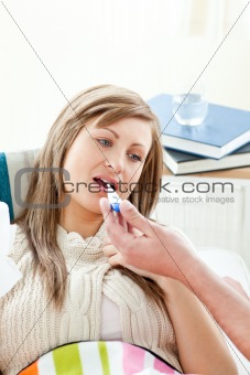 Young sick woman with thermometer lying on a sofa with her boyfriend