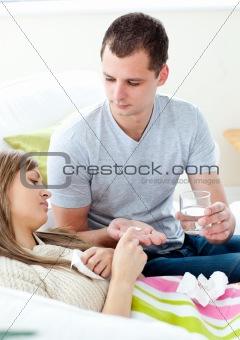 Caring man giving his sick girlfriend pills and water