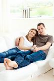 Loving couple lying on the sofa smiling at the camera