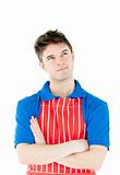 Serious young cook wearing a apron with folded arms 