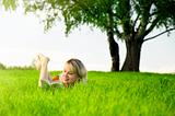 Young beautiful woman lays on green field