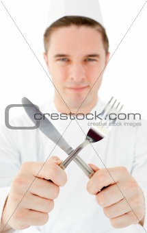 Handsome cook holding cutlery