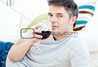 Handsome man lying on the floor drinking wine 