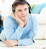 Positive man with headphones lying on the floor
