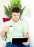 Concentrated young man using his laptop drinking coffee