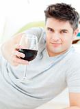 Smiling young man lying on the floor drinking wine in the living room