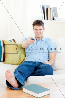 Relaxed young man holding a remote sitting on the couch