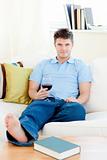 Charming man holding a wineglass sitting on the sofa 