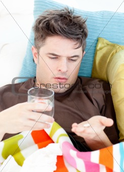 Sick caucasian man taking pills with water 