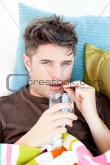 Diseased caucasian man taking pills with water