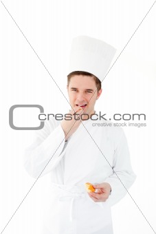 Smiling male chef eating fresh bread looking at the camera 