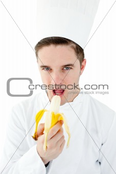 Confident male cook eating a banana 