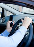 Close-up of a cute young man sending a message with his mobile phone sitting in his car