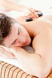 Attractive man enjoying a massage with hot stone 