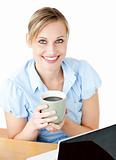 Glowing businesswoman drinking coffee smilng at the camera 