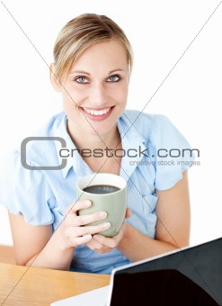 Glowing businesswoman drinking coffee smilng at the camera 