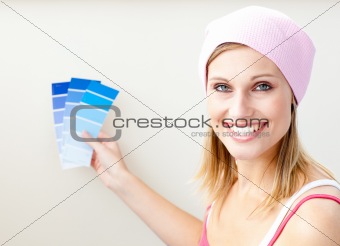Joyful young woman choosing color for painting a room 