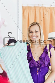 Happy blond woman looking at a shirt in a clothes store 