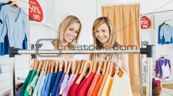 Joyful female friends choosing colorful shirts 