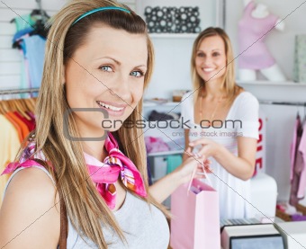 Merry young woman getting shopping bags from the saleswoman 