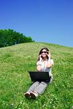 Woman with notebook and  phone sit on hill