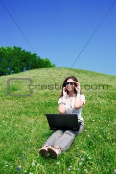 Woman with notebook and  phone sit on hill