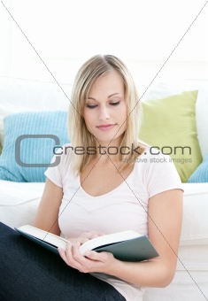 Concentrated young woman reading a book on the floor 
