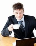 Charismatic businesman drinking coffee using his laptop 