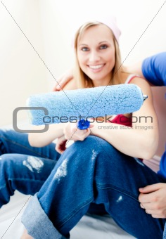 Cheerful woman holding a paint brush into the camera 