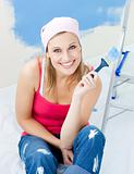 Joyful young woman holding a paint brush smiling at the camera 