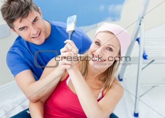 Hugging couple having fun while painting a room